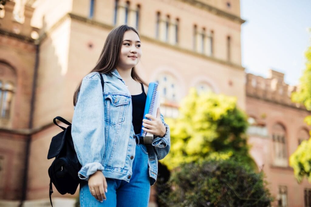 student girl outside in summer park smiling happy. asian female college or university student. mixed race asian young woman model wearing school bag.