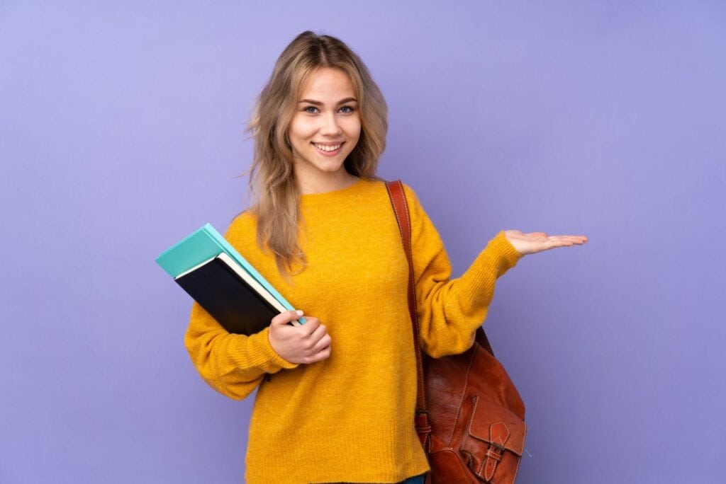 teenager russian student girl isolated on purple background holding copyspace imaginary on the palm to insert an ad